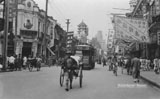 Foochow Road showing trolley bus, rickshaws and pedicabs. Note the banners used for advertising by day, at night neon signs lit up the street.