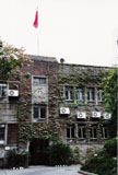 A picture of the Shanghai Jewish School covered partly with vegetation, taken on a return visit years later.
